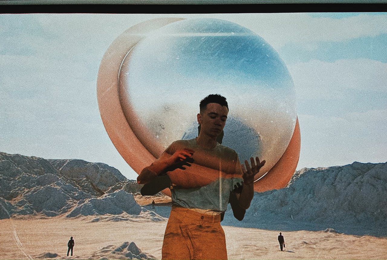 A surreal image of a man with eyes closed, holding a sphere in a desert landscape.