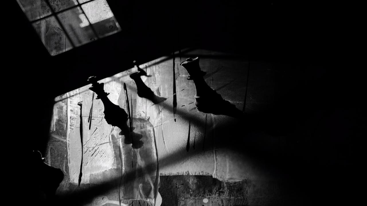 Artistic black-and-white photo of chess piece shadows creating a dramatic and mysterious ambiance.